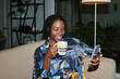 Portrait of smiling Black woman drinking tea and reading post on social media
