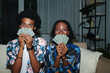 Funny young Black couple posing with playing cards