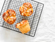 Homemade brioche buns with almond petals on a baking rack on a light background, top view
