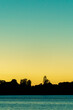 Silhouette land and trees on horizon under colourful sunrise sky