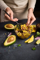 Wall Mural - Woman mixing chopped tuna, mango, cilantro and onion in a glass bowl cooking traditional tuna and mango tartare