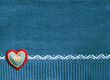 Wool sweater texture of teal color with white border and felt heart. Natural knitted wool material with decor. Horizontal Christmas background with knitted fabric texture. Warm winter time backdrop