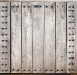 Wall Mural - Detail of old wooden gate leaf part. Decorative square background with ancient wood shutter with metal rivets. Copy space for text