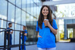 While walking to work in a city hospital, a young female nurse holding coffee to go.  Female medical staff wearing stethoscope relaxing outdoor. Doctor woman drinking coffee.
