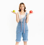 Fototapeta  - Charming joyful girl holding apple with measuring tape on white background, vitamins for healthy skin.