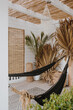 Cozy hammock, dried palm leaves. Aesthetic bohemian interior with natural straw and palm. Boho styled luxury resort hotel. Summer vacation holidays