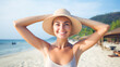 A woman is smiling and wearing a straw hat on a beach