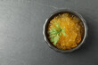 Fresh pike caviar in bowl on black table, top view. Space for text