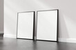 Two empty picture frames resting on a wooden floor against a white wall, suitable for art display or mockup design, 3d render.