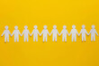 A row of paper people holding hands on yellow background