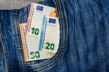 Wall Mural - Three folded 50 Euro banknote bills stuck in front pocket of blue jeans