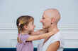 Young girl look affectionately at a bald woman ill of cancer