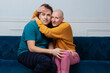 Happy woman with no hair and her husband cuddling on velvet sofa