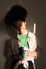 Wall Mural - An attractive young girl of mixed race holds a cup of coffee and smiles