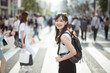 Tokyo hustle, Unrecognizable Asian woman traveler crossing the urban road, snapshot of modern city life.