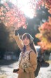 Kyoto's fall beauty, Asian woman in a casual dress enjoys a holiday, capturing the vibrant foliage, cheerful smiles, and the beauty of Kyoto's scenic destinations.