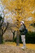 Asian woman in casual dress revels in the beauty of fall, adorned in a lovely sweater. A joyful portrait amid nature's colorful backdrop, radiating cheer and happiness.