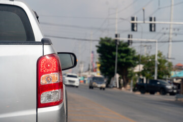 Wall Mural - Pickup car silver color on the road stop and turn on brake light. Traffic light on the road. Blur image of traffic jam.