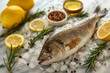 A fish is displayed on a table with lemon slices and herbs