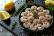 A bowl of shrimp with lemon slices and herbs on a black table