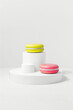 Two delicious macarons are stacked on a white podium cylindrical pedestals, creating a colorful display. Mock up stand for product presentation. Minimal concept. Advertising template 