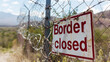 Grungy border closed warning sign on fence with barbed wire with copy space for text. Concept of illegal immigration control and security