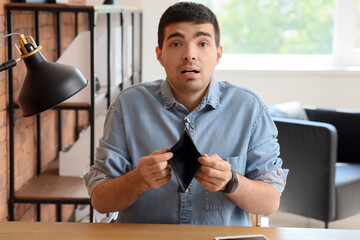 Wall Mural - Upset young man with empty wallet in office