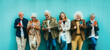 Group of senior people using technology devices together standing on a blue wall - Happy older friends having fun watching funny video on smartphone - Tech and modern elderly concept