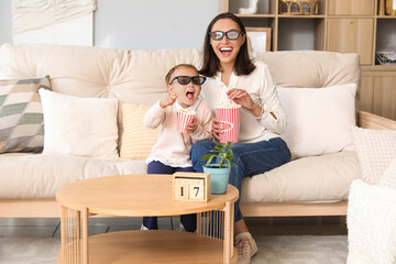 Canvas Print - Beautiful mother and her cute little daughter in 3D cinema glasses with popcorn watching movie at home