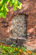 Arched niche in an antique red brick wall among autumn yellow-green foliage, vertical. Vintage brick background on Small Maximilian Tower 3 Ruins in Lviv, Ukraine