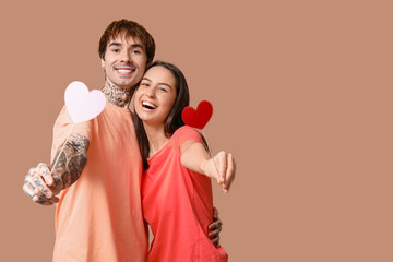 Poster - Young couple with paper hearts on beige background