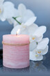 Spa background with white orchid  and  candle  on gray.