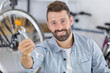 man showing a spanner while fixing a bicycle wheel