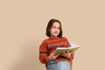 Sticker - Little girl reading book while sitting on chair near beige wall