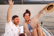 Couple waving to friends while sailing on a boat