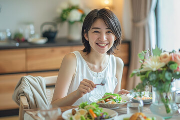 Wall Mural - A Japanese woman in her thirties is smiling while eating, with short hair and wearing white. She is sitting at the dining table of an all-white modern minimalist kitchen