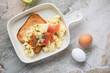 Beige serving tray with scrambled eggs and smoked salmon on toast, top view on a grey granite background, horizontal shot