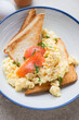 Toasts with scrambled eggs and smoked salmon served in a blue and white plate, vertical shot, middle closeup, selective focus