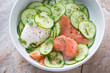 Cucumber salad with smoked salmon and poached egg in a white bowl, horizontal shot, middle closeup, selective focus