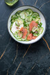 Bowl with smoked salmon and cucumber salad, above view on a dark-green marble background, vertical shot, copy space