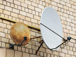 Old satellite dish on the wall of the house.