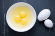 Raw chicken and goose eggs on a black marble background, horizontal shot, above view