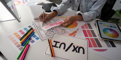 Wall Mural - stylish woman ux designer using digital tablet and computer planning new website wireframe at creati