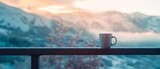 Fototapeta  - Serene winter morning, with a cup of hot coffee placed on a balcony railing, mountain view in the frosty background, perfect for peaceful day starts