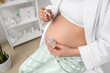© Pixel-Shot - Young pregnant woman applying serum on her tummy in bathroom, closeup