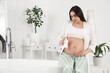 © Pixel-Shot - Young pregnant woman with bottle of cream in bathroom