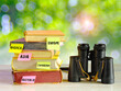 stack of travel Guides,travel books,guidebooks for various destinations and vintage binoculars on blurred nature background,free copy space