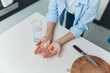 © SHOTPRIME STUDIO - Woman holding pills and a knife next to a glass of water on a white table Concept of medication and selfharm