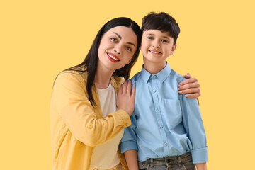 Sticker - Mother hugging her little son on yellow background