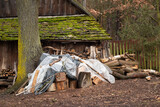 Fototapeta Młodzieżowe - Logs of wood and chopped wood against the background of an old wooden building, village, retro. Stack of wood covered with foil.
